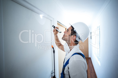 Side view of worker using flashlight in hallway