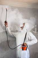 Manual worker using pest spray on wall