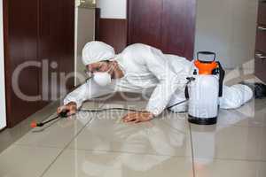 Pest worker using sprayer in kitchen