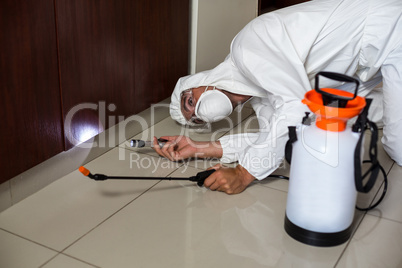 Worker using flashlight under cabinet