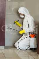Side view of worker using insecticide on wall