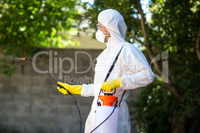 Side view of worker using pesticide in back yard