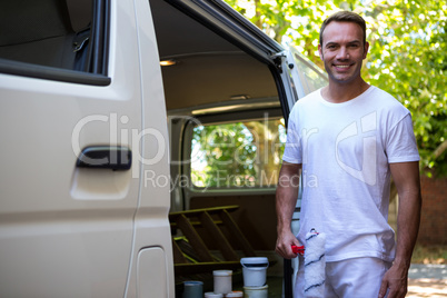 Painter holding paint roller standing near his van