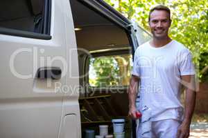 Painter holding paint roller standing near his van