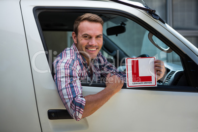 Young man holding a learner driver sign