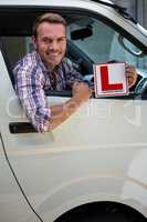 Young man holding a learner driver sign