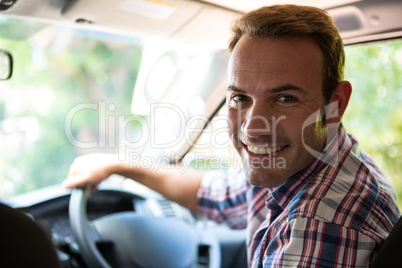 Young man looking at camera while sitting on cars front seat