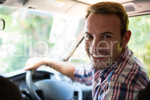 Young man looking at camera while sitting on cars front seat