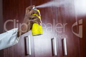 Hand spraying pesticide from a spray can