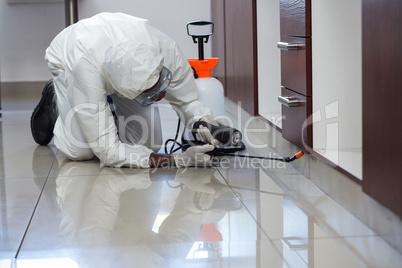 Pest control man spraying pesticide under the cabinet