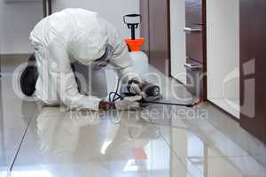 Pest control man spraying pesticide under the cabinet