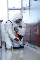 Pest control man spraying pesticide under the cabinet
