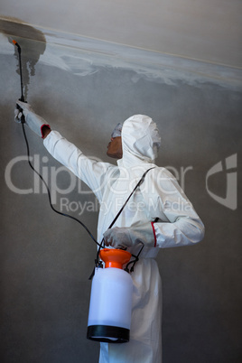 Man doing pest control on a wall