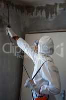 Man doing pest control on a wall