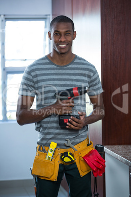 Smiling manual worker holding a drill machine