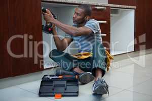 Manual worker drilling a hole in kitchen