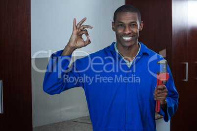 Plumber with a wrench showing ok hand sign