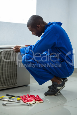 Handyman testing air conditioner with screwdrive