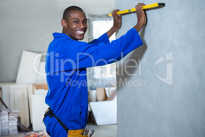 Happy handyman measuring a wall with spirit level