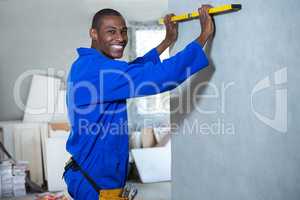 Happy handyman measuring a wall with spirit level