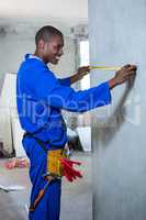 Happy handyman measuring a wall