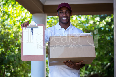 Delivery man holding parcel and clipboard