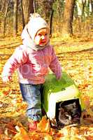 baby plays with her cat in cage in the Autumn park