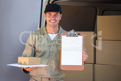 Happy delivery man holding cardboard box and clipboard