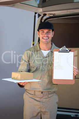 Happy delivery man holding cardboard box and clipboard