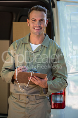 Happy delivery man writing on a clipboard