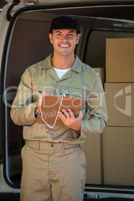 Happy delivery man writing on a clipboard