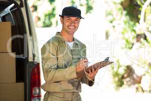 Happy delivery man writing on a clipboard