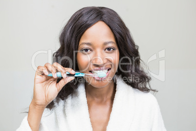 Portrait of a young woman brushing her teeth