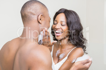 Young woman applying foam on young mans face