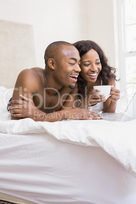 Young man using a laptop and woman holding coffee cup