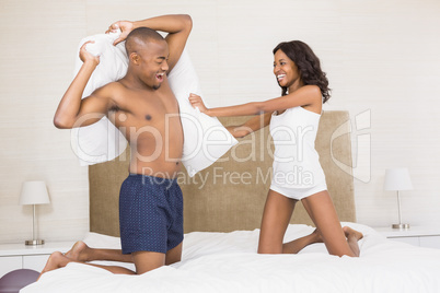Young couple having a pillow fight Young couple having a pillow fight