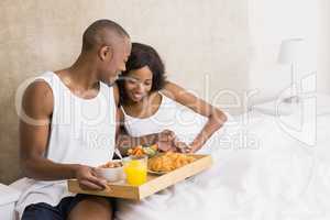 Young man serving breakfast to woman