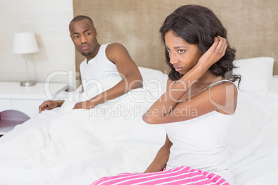 Young woman sitting on bed after an argument