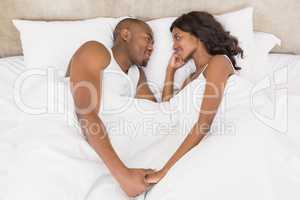 Young couple lying face to face on bed