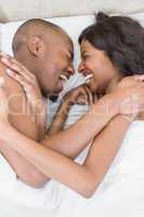 Young couple lying on bed face to face and laughing