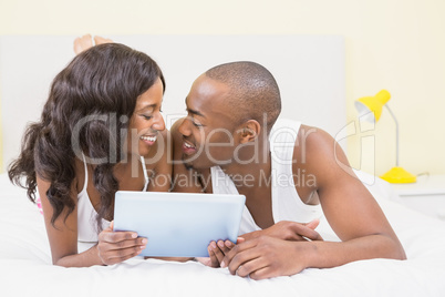 Young couple looking face to face and holding digital tablet