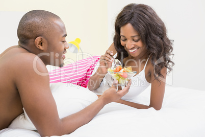 Young man offering fruit bowl to woman