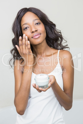 Young woman applying moisturizer