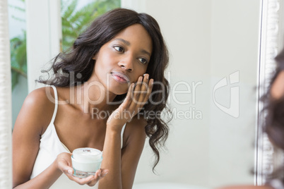 Young woman applying moisturizer