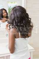 Young woman straightening hair