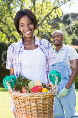 Young woman holding a basket of freshly harvested vegetables