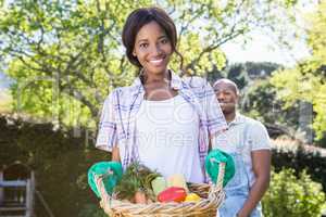 Young woman holding a basket of freshly harvested vegetables