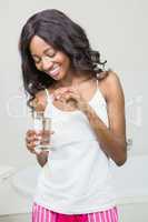 Beautiful woman putting pill in to a glass of water