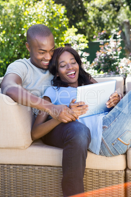 Young couple relaxing on the sofa and using digital tablet