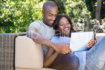 Young couple relaxing on the sofa and using digital tablet